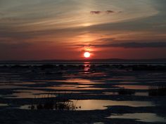 the sun is setting over an icy lake