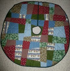 a quilted table top on the floor with red and green squares, dots and circles