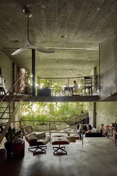 a living room filled with furniture and lots of plants on top of the walls next to a stair case