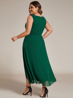 a woman in a green dress is standing and looking at the camera with her hands on her hips