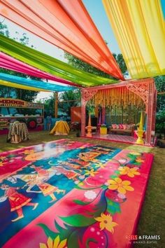 an elaborately decorated dance floor in the middle of a lawn with colorful draping