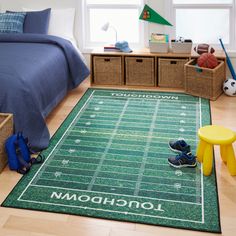 a football field rug in a child's bedroom with toys on the floor and storage bins