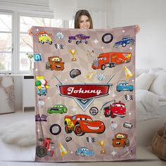 a woman holding up a blanket with cars on it