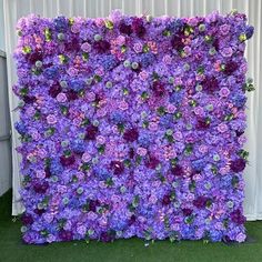 purple flowers are arranged on the side of a wall