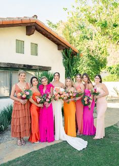 a group of women standing next to each other on top of a grass covered field