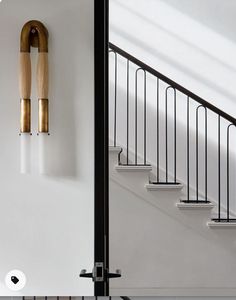 an open door leading to a white staircase with black railing and wooden handrails