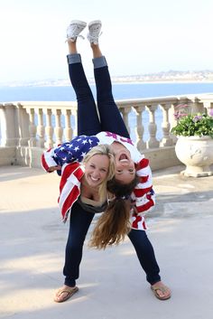 two women are doing handstand in front of an american flag shirt and jeans