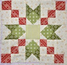 a green and red patchwork quilt with an arrow on the center, surrounded by smaller squares