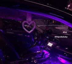 the interior of a car is lit up with purple lights and heart - shaped decorations