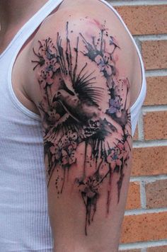 a man's arm with a bird and flowers tattoo on the left side of his arm