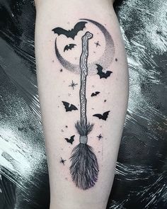 a black and white photo of a tatoo with bats flying around it on the leg