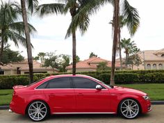 a red car parked in front of some palm trees