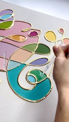 a person is drawing on a piece of paper with colored circles and shapes in it