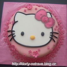 a hello kitty cake with pink icing and flowers on it's side, in the shape of a circle