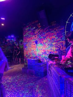 some people in a room with neon paint on the walls and djs behind them