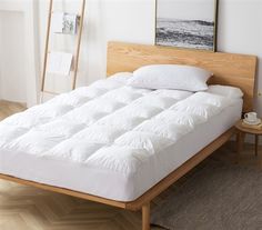 a white bed sitting on top of a wooden frame