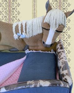 a stuffed horse sitting on top of a blue couch next to pillows and blanketes