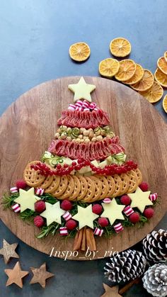 a christmas tree made out of crackers on a wooden platter next to pine cones and orange slices