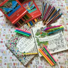 there are many books and pencils on the bed with colorful papers in front of them