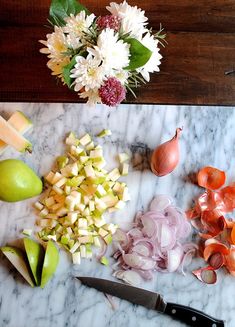 an assortment of fruits and vegetables cut up on a marble cutting board with a knife