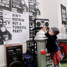 a young boy standing next to a silver fire hydrant in front of a wall with posters on it