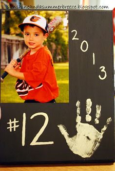 a child's handprint is displayed on a wooden frame with a baseball player