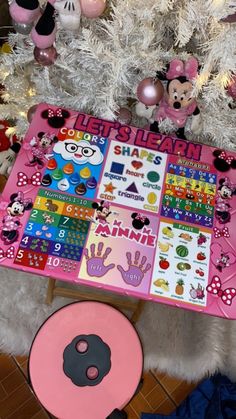 a pink table with mickey mouse stickers on it next to a white christmas tree