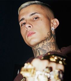 a man with tattoos on his arm holding a gold object in front of the camera