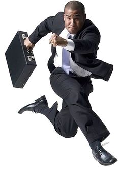 a man in a suit and tie jumping into the air with a briefcase behind him