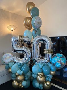 the balloon number 50 is surrounded by blue and gold balloons in front of a couch