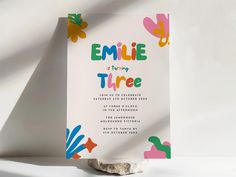 an image of a birthday party card with flowers on the front and back cover that says, emile is turning three