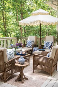 an outdoor patio with wicker furniture and blue and white pillows on the back deck