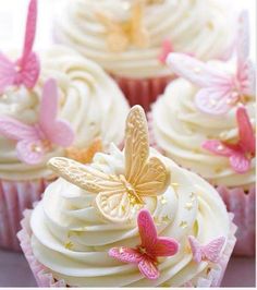 cupcakes with white frosting and pink butterflies on the top one is decorated