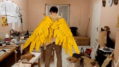 a man standing in a room with yellow wings on his back