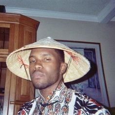 a man wearing a straw hat standing in front of a wooden cabinet and cupboards