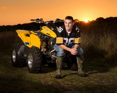 a man sitting on the ground next to a yellow four - wheeler atv at sunset