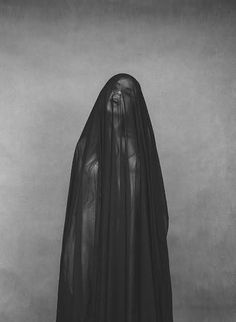 a black and white photo of a woman wearing a long veil with her head down