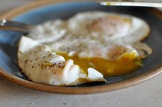 two fried eggs are on a plate with a fork and knife in the bowl, ready to be eaten