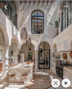 an open kitchen and dining area with white walls, arched doorways, and large windows