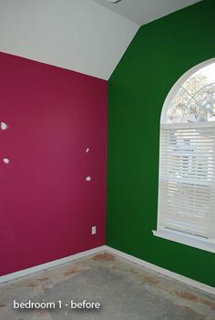 an empty room with pink and green paint on the walls, and white shutters in the window