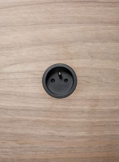 a wooden surface with a black button on the center and two holes in the middle