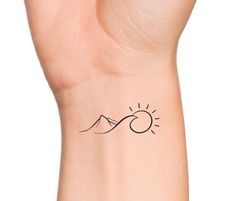 a woman's wrist tattoo with the sun and mountains on it, in black ink