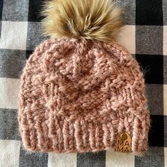 a knitted hat with a pom - pom sitting on top of a checkered table cloth