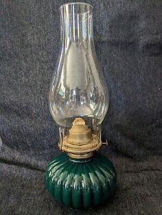 an old fashioned glass oil lamp on a black cloth covered surface with a green base