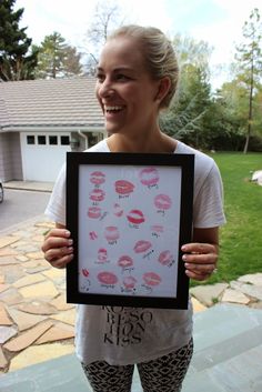 a woman holding up a framed photo with pink lipstick on it's lips in front of her face