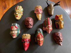 seven colorful masks are arranged on a black surface