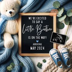 a baby announcement with a teddy bear next to it and some blue shoes on the ground