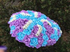 blue and purple wedding bouquet on top of a tree in front of some shrubbery