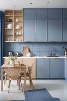 a kitchen with blue cabinets and wooden table in the center, white tile flooring