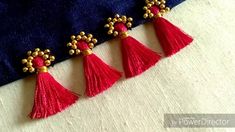 three red tassels are hanging from a blue piece of cloth with gold accents